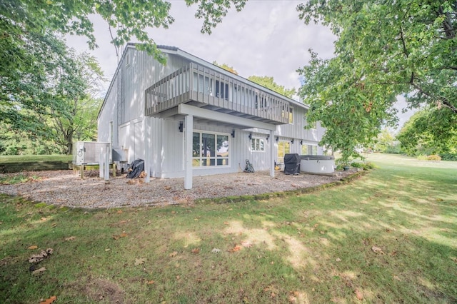 rear view of property featuring a lawn and a jacuzzi