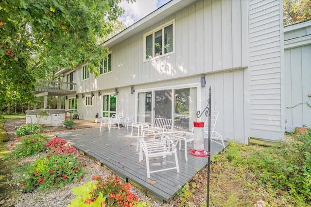 back of property featuring a wooden deck and a hot tub