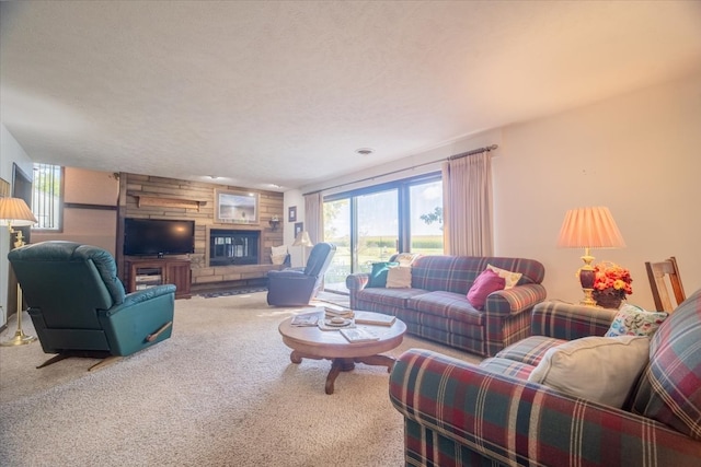 living room with a textured ceiling, carpet, and a stone fireplace