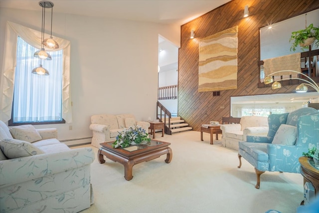 living room featuring carpet floors, wooden walls, a baseboard heating unit, and a wealth of natural light