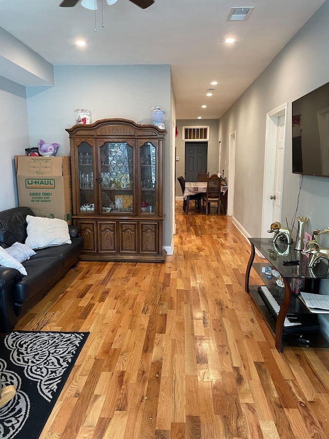 living room with light wood-type flooring and ceiling fan