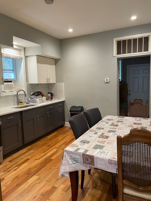 dining space with sink, light hardwood / wood-style flooring, and cooling unit