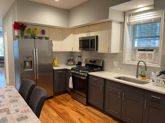 kitchen featuring cooling unit, white cabinetry, light wood-type flooring, sink, and stainless steel appliances