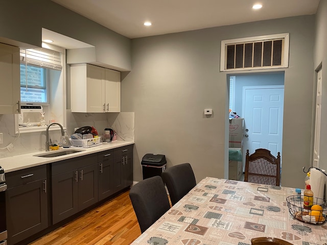 kitchen with sink, white cabinetry, and light hardwood / wood-style flooring