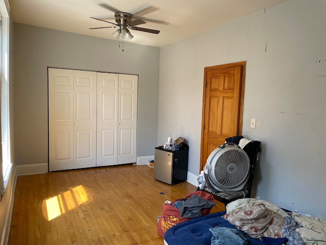 bedroom featuring a closet, stainless steel fridge, light wood-type flooring, and ceiling fan