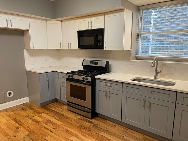 kitchen with gray cabinets, sink, gas stove, and light hardwood / wood-style floors