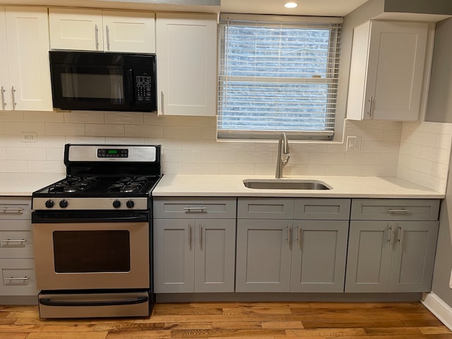 kitchen featuring gray cabinets, sink, gas stove, and light hardwood / wood-style floors