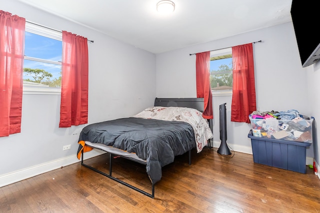 bedroom with multiple windows and hardwood / wood-style flooring