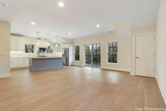 unfurnished living room with light hardwood / wood-style floors and vaulted ceiling