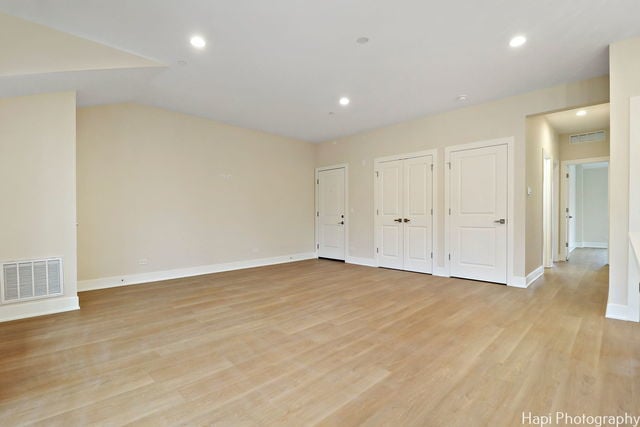 unfurnished bedroom with light wood-type flooring and two closets