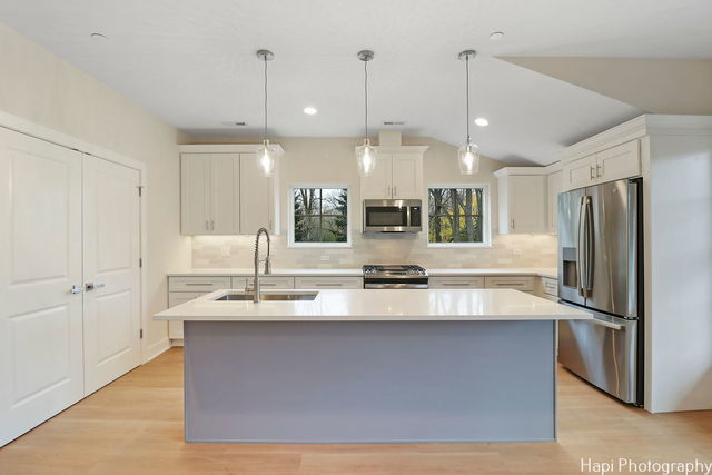 kitchen with white cabinetry, sink, stainless steel appliances, an island with sink, and pendant lighting