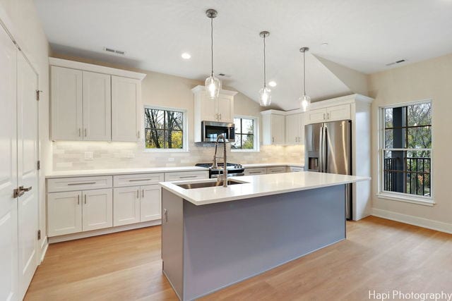 kitchen featuring decorative backsplash, white cabinetry, stainless steel appliances, and decorative light fixtures