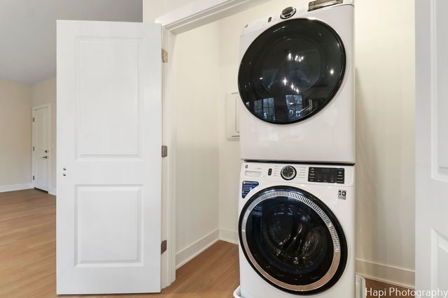 laundry area with wood-type flooring and stacked washer and dryer