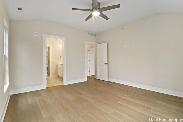 unfurnished bedroom with ensuite bathroom, light hardwood / wood-style flooring, ceiling fan, and lofted ceiling