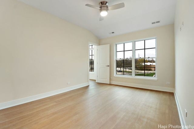 empty room featuring light wood-type flooring, vaulted ceiling, and ceiling fan