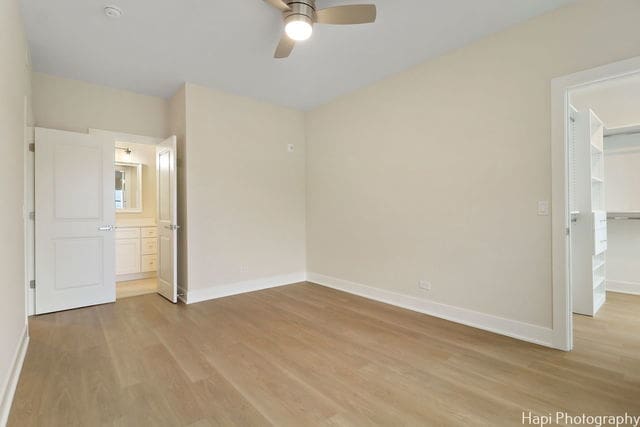 unfurnished bedroom with ceiling fan, a closet, a spacious closet, and light hardwood / wood-style flooring