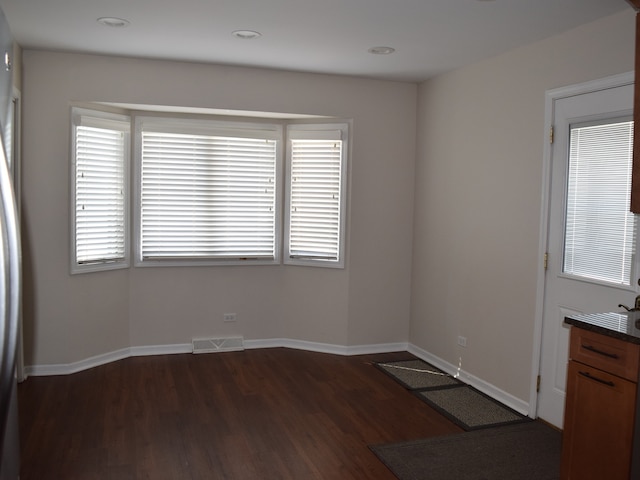 empty room with dark hardwood / wood-style flooring and a healthy amount of sunlight