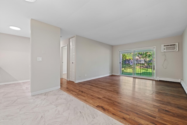 empty room featuring a baseboard heating unit, light wood-type flooring, and a wall unit AC