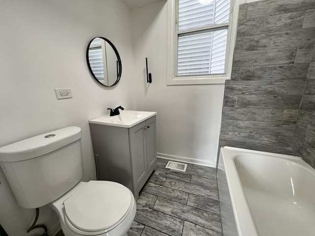 bathroom with vanity, a tub to relax in, and toilet