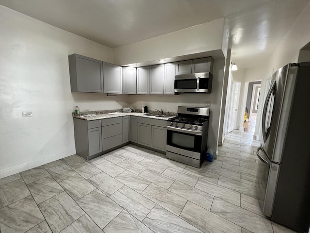 kitchen featuring stainless steel appliances, sink, and gray cabinetry