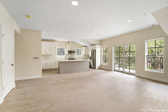 unfurnished bedroom with light hardwood / wood-style floors, ensuite bathroom, and lofted ceiling