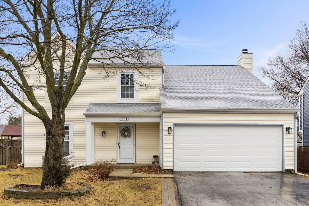 view of front of house featuring aphalt driveway, roof with shingles, a chimney, fence, and a garage