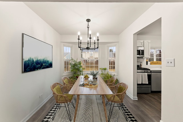 dining space featuring dark wood-style flooring, baseboards, and an inviting chandelier