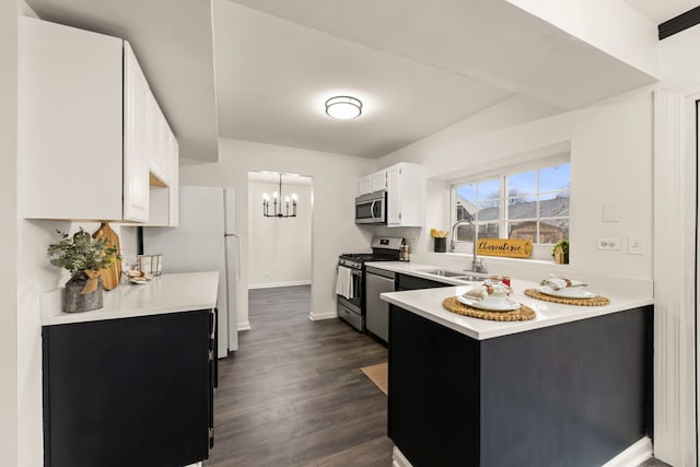 kitchen featuring appliances with stainless steel finishes, a peninsula, an inviting chandelier, light countertops, and a sink