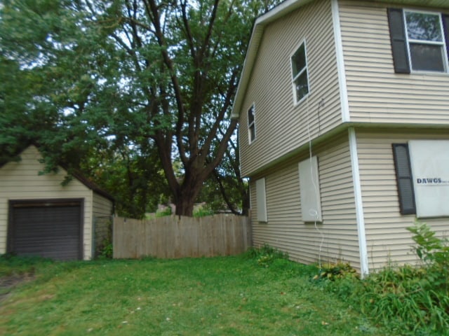 view of home's exterior featuring a garage, a yard, and an outbuilding