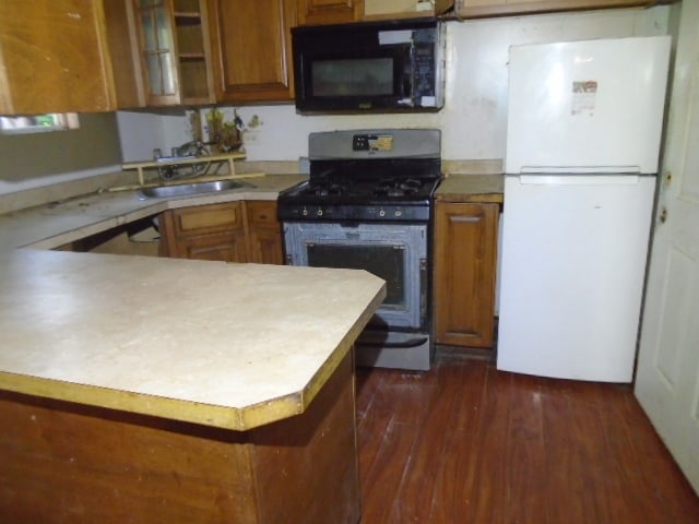 kitchen with sink, dark hardwood / wood-style floors, kitchen peninsula, and black appliances