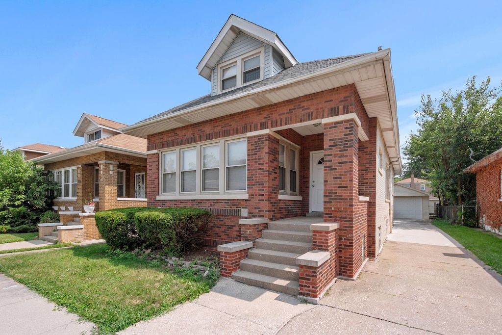 view of front facade with a front yard, brick siding, and an outdoor structure