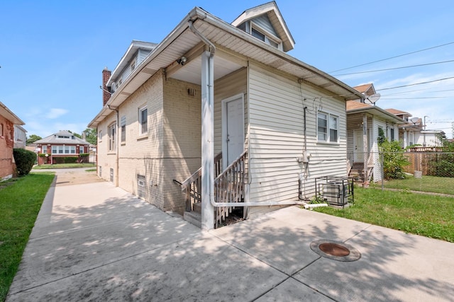 exterior space with entry steps, a patio, brick siding, fence, and a lawn