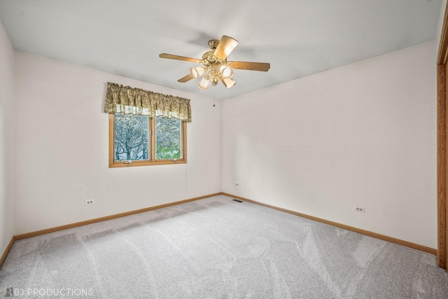 carpeted spare room with a ceiling fan, visible vents, and baseboards