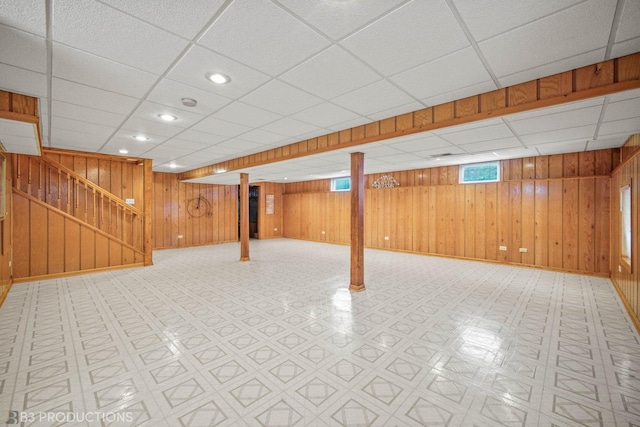 below grade area featuring recessed lighting, wood walls, baseboards, stairway, and tile patterned floors