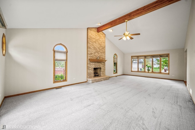 unfurnished living room with a brick fireplace, beam ceiling, brick wall, light carpet, and ceiling fan