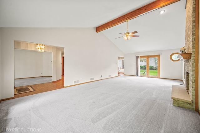 unfurnished living room with high vaulted ceiling, a fireplace, ceiling fan with notable chandelier, and carpet flooring