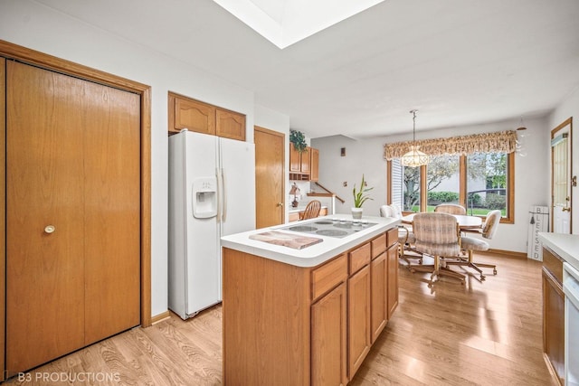 kitchen featuring white appliances, light wood-style floors, light countertops, a center island, and decorative light fixtures