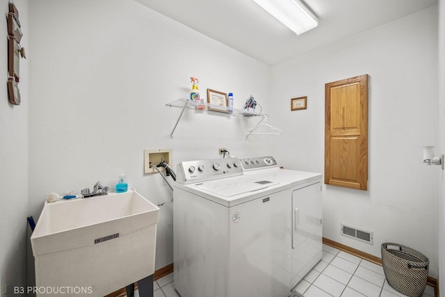 clothes washing area featuring light tile patterned floors, laundry area, a sink, visible vents, and washer and clothes dryer