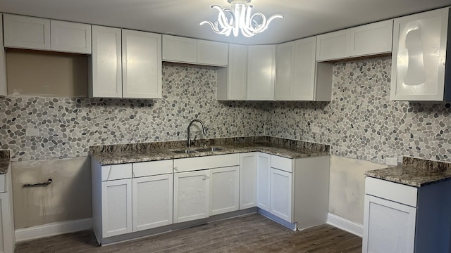 kitchen featuring a chandelier, dark wood-style flooring, a sink, white cabinetry, and tasteful backsplash