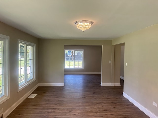 unfurnished room with dark wood-type flooring and a notable chandelier