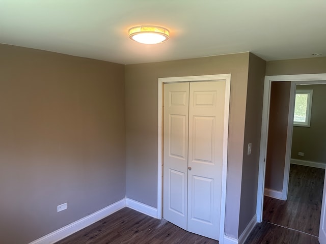 unfurnished bedroom with a closet and dark wood-type flooring