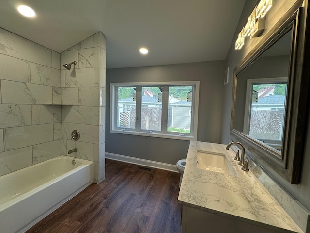 full bathroom with vaulted ceiling, wood-type flooring, tiled shower / bath combo, vanity, and plenty of natural light