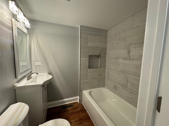 full bathroom featuring hardwood / wood-style floors, tiled shower / bath combo, toilet, and vanity