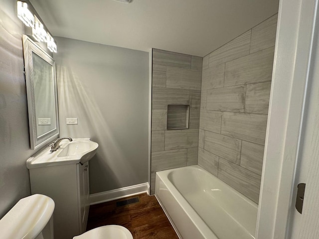 full bathroom featuring vanity, hardwood / wood-style floors, tiled shower / bath, and toilet