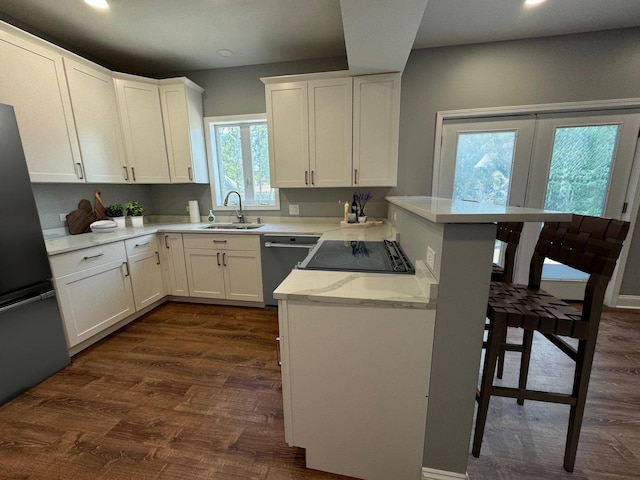 kitchen with sink, stainless steel refrigerator, dishwasher, kitchen peninsula, and white cabinets