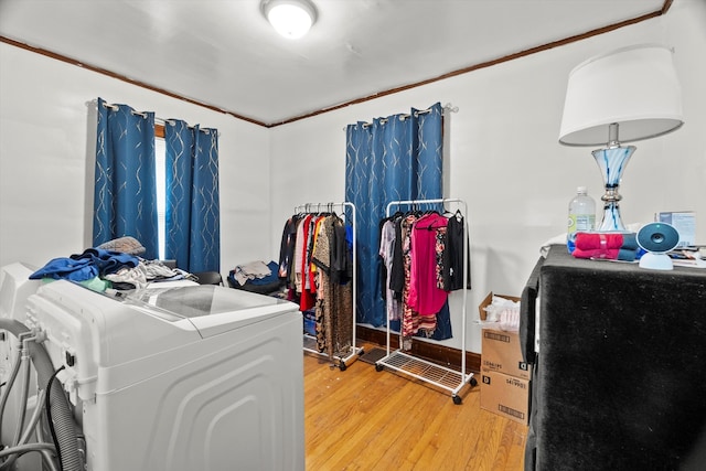 laundry area with washer and clothes dryer, ornamental molding, and light hardwood / wood-style floors