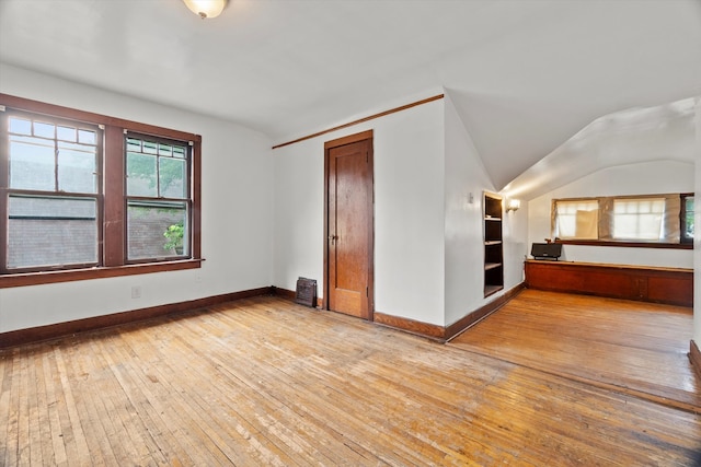 empty room with light wood-type flooring and vaulted ceiling