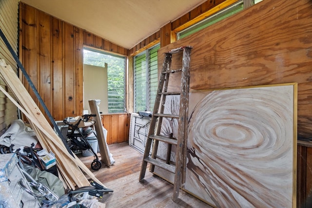 interior space featuring wood walls, light hardwood / wood-style flooring, and lofted ceiling