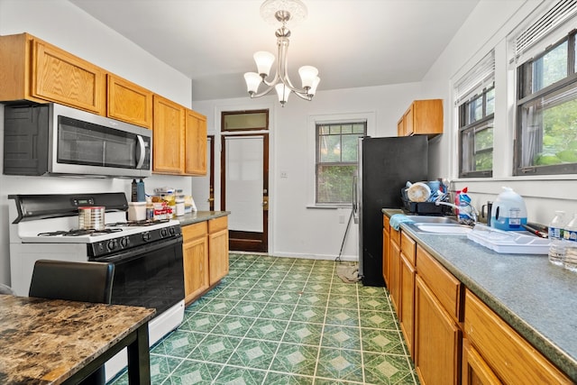 kitchen with pendant lighting, tile patterned floors, white gas stove, and a wealth of natural light