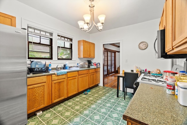 kitchen featuring appliances with stainless steel finishes, sink, hanging light fixtures, dark hardwood / wood-style flooring, and a notable chandelier